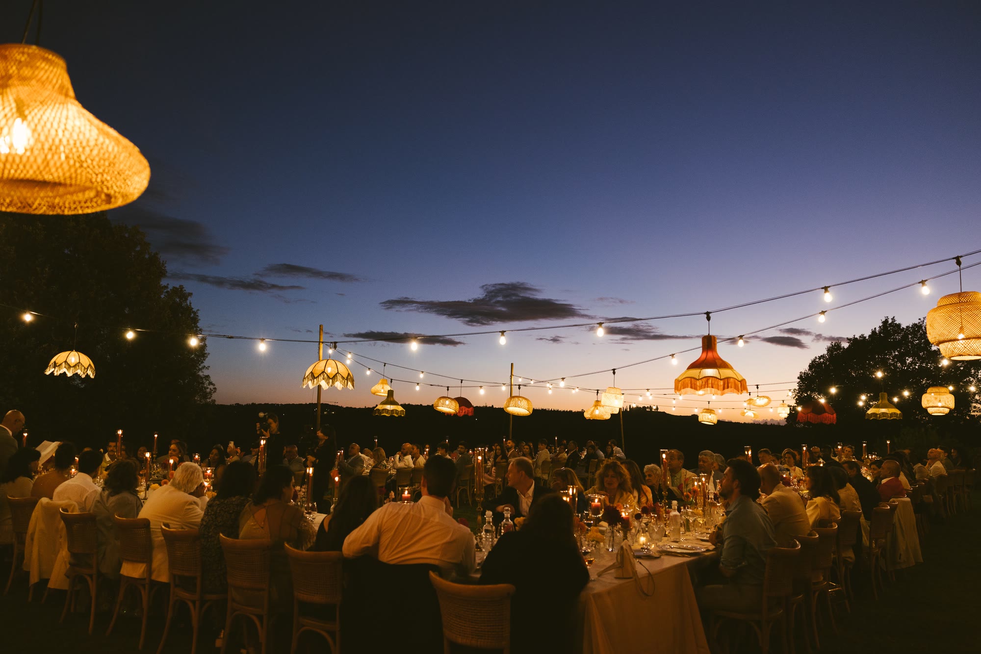 Dinner on the terrace at night, the long table lit, the hills dark behind
