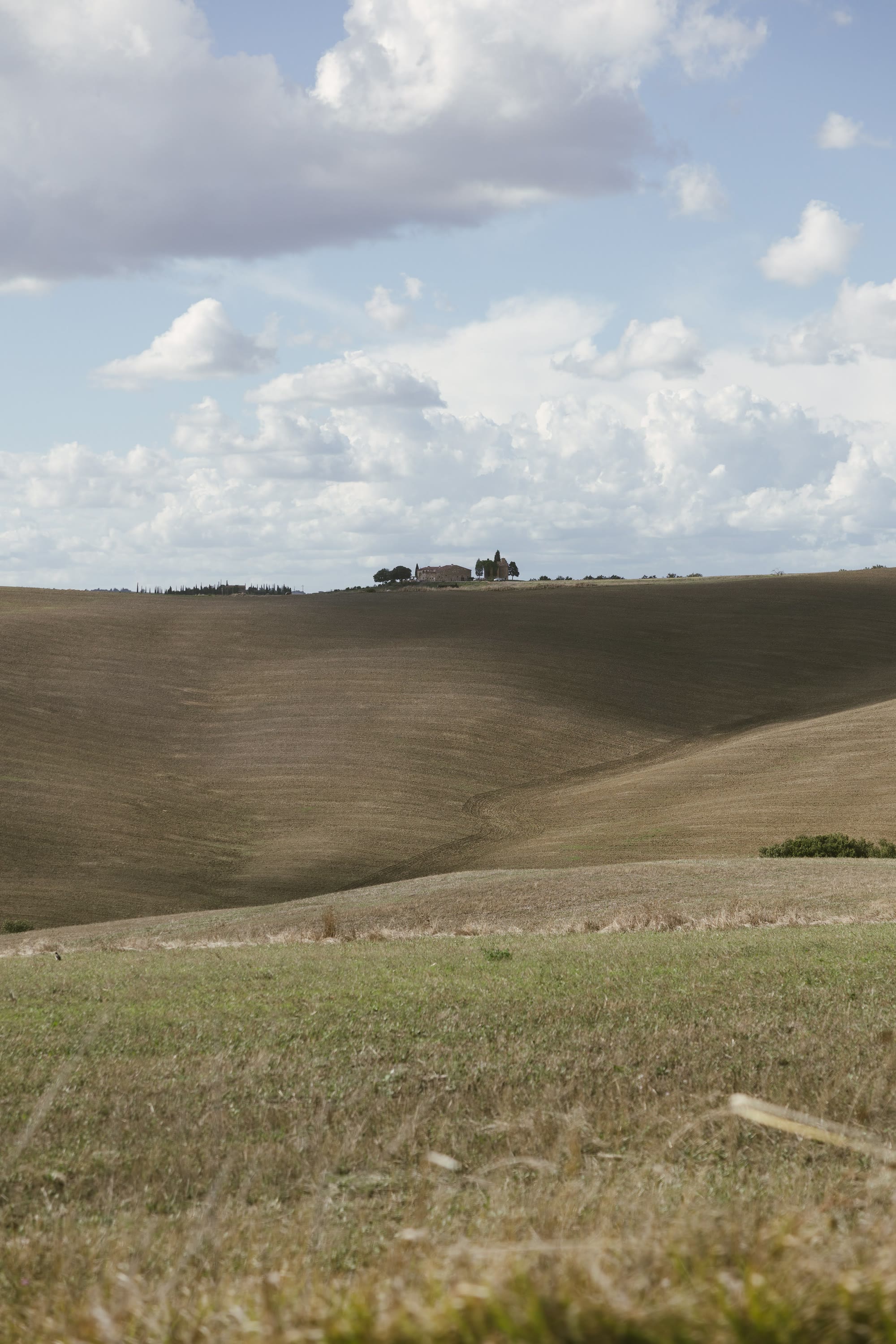 Le colline spoglie della Val d'Orcia sotto un cielo d'estate