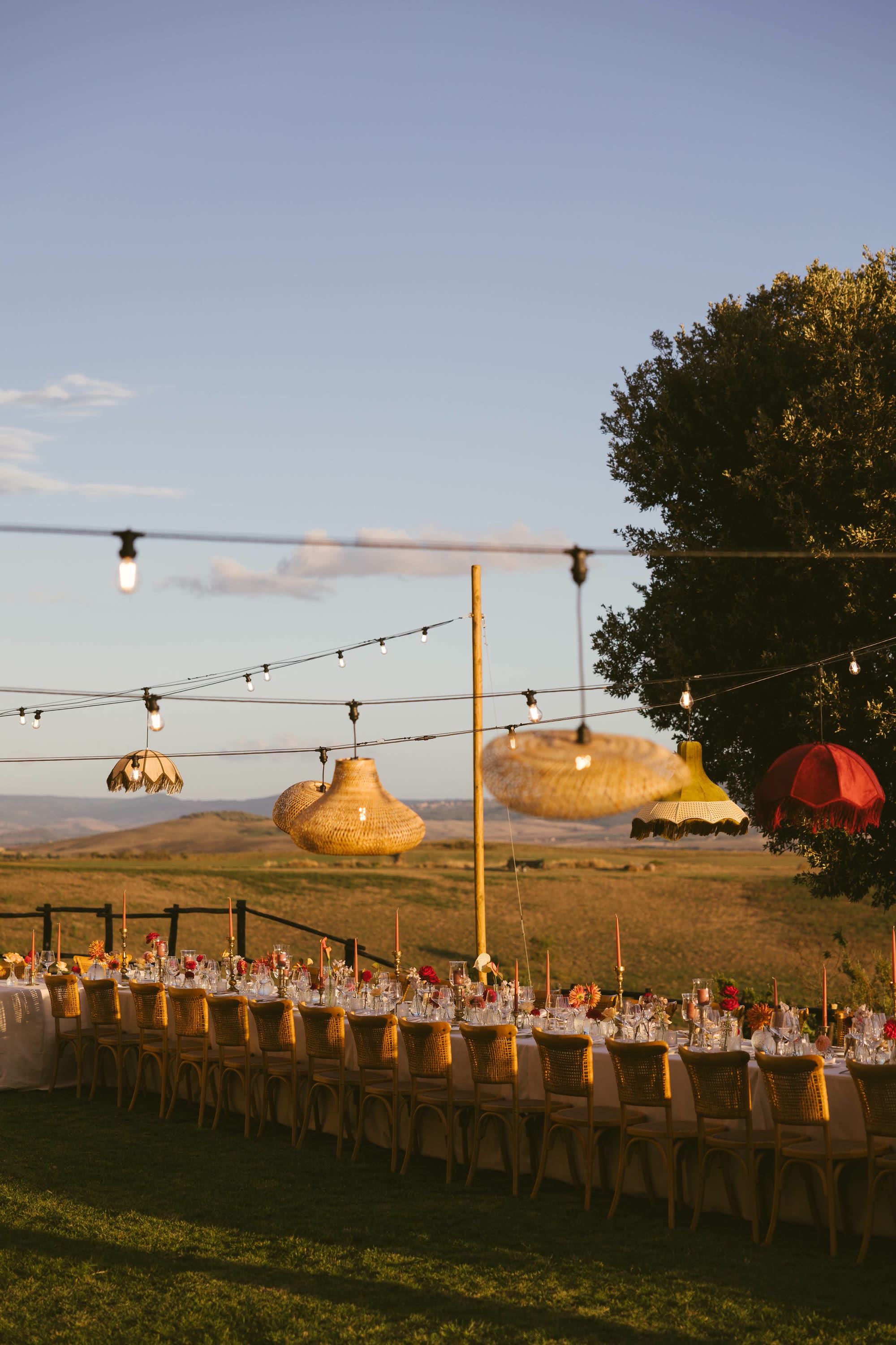 String lights and parasol lanterns over the long table at dusk
