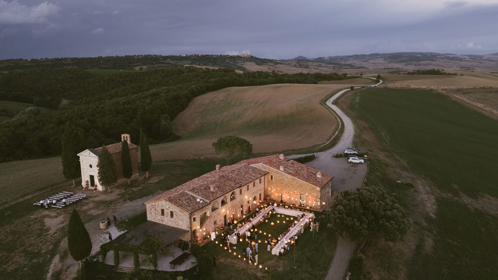 La villa al crepuscolo vista dall'alto, con la lunga tavola illuminata sotto le lanterne