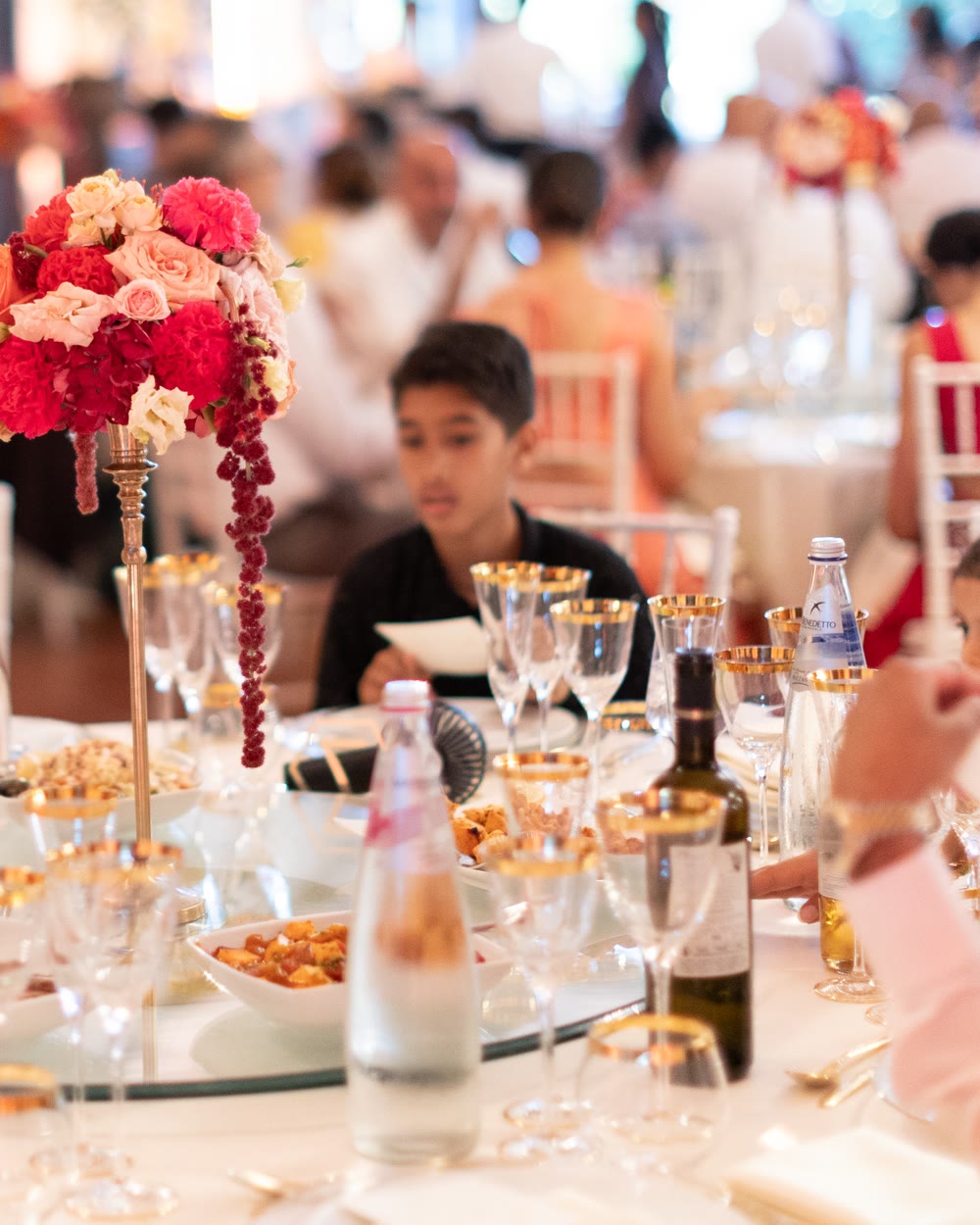 Guests at round tables with tall flower centrepieces at a reception