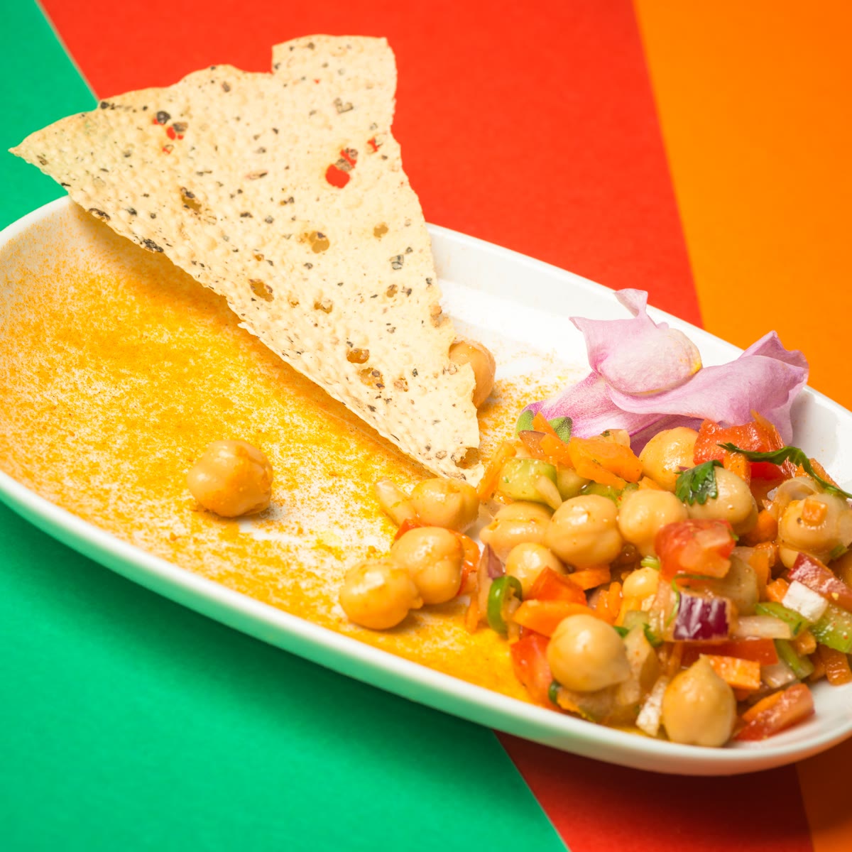 Chickpea chaat with a papadam on a white dish