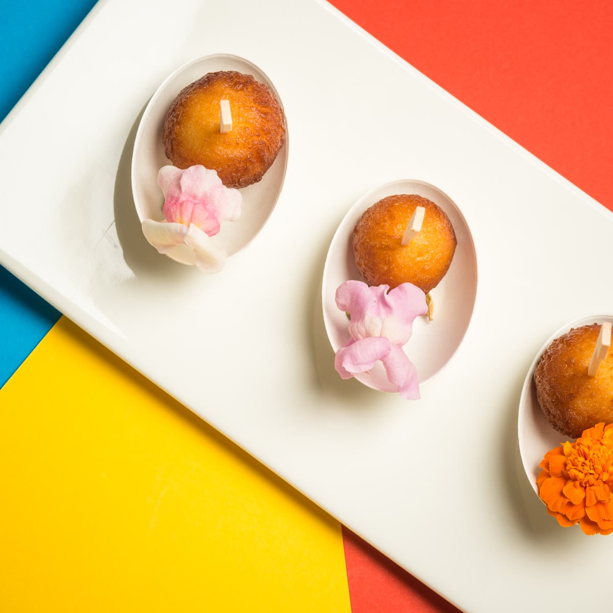 Three gulab jamun in white spoons with rose petals