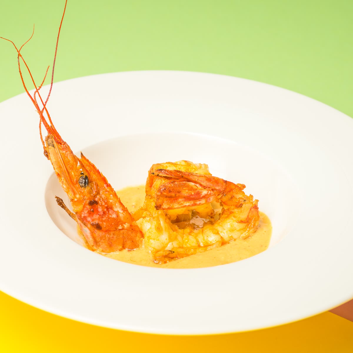 A king prawn in a curry sauce on a white plate