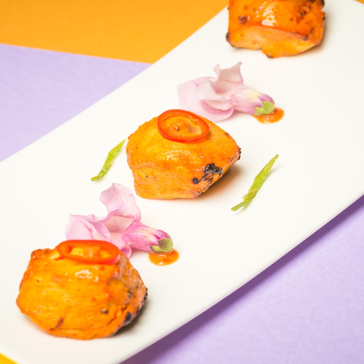 Cubes of chilli paneer with a slice of red chilli