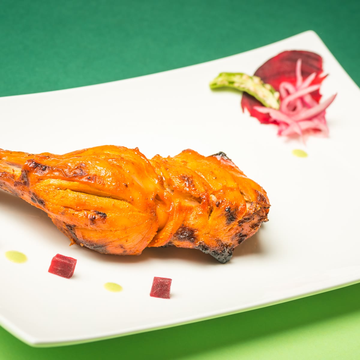 A tandoori chicken leg with beetroot and pickled onion