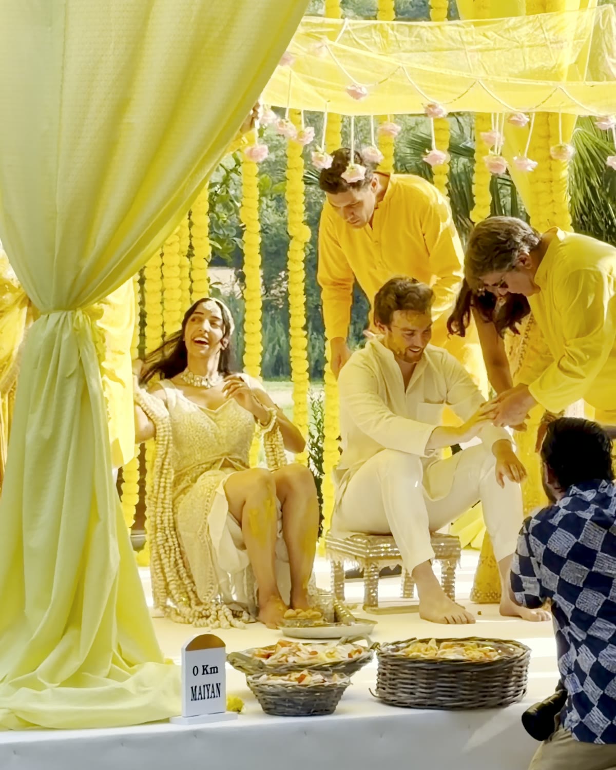 Family and friends apply turmeric to the couple under a yellow canopy at Villa Corbinaia
